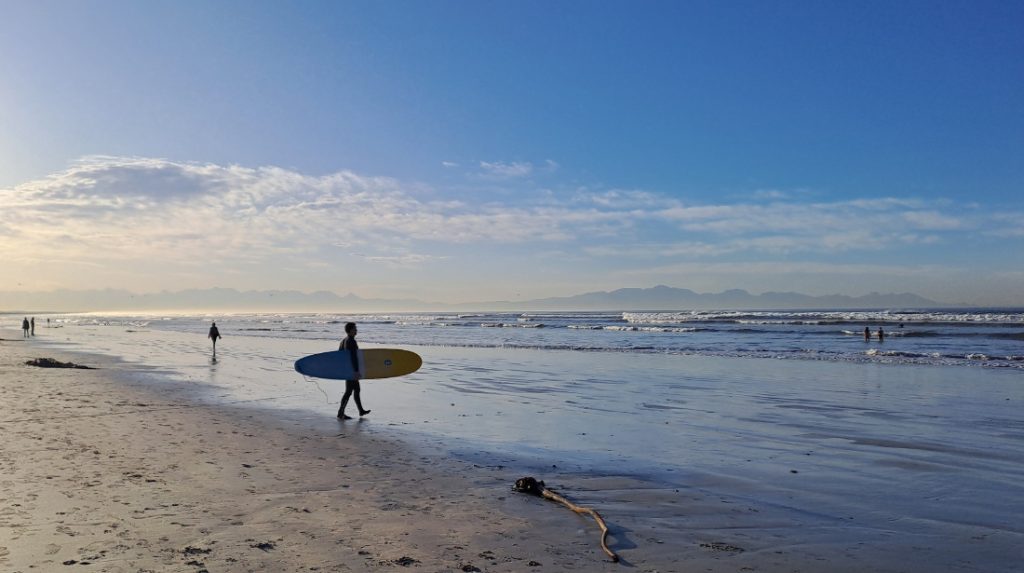 surfer walking to the water on Muizenberg Beach